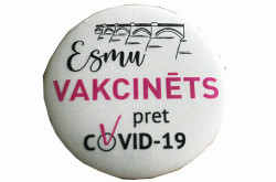 Kuldīgas slimnīcas vakcinēšanas kabinets vieglatlētikas manēžā pēc otrās potes iedzīvotājiem dāvina vēstneša nozīmītes "Esmu vakcinēts pret Covid-19".